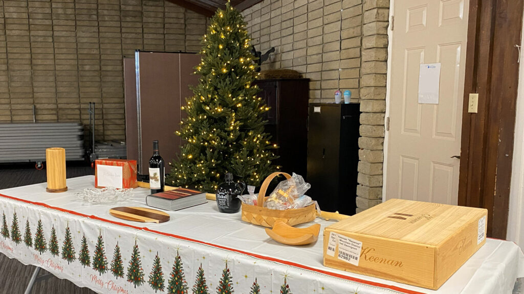 A dozen raffle prizes and a Christmas tree in the background during the TVC winter holiday party.