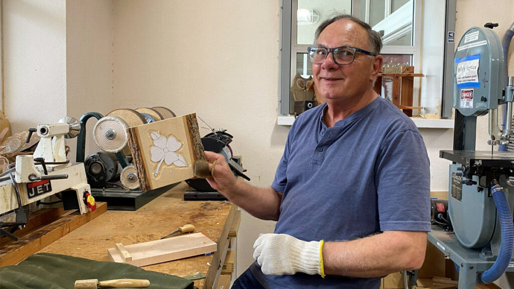 Grant is carving a flower on a live-edge basswood board using the relief carving style.