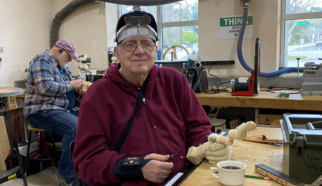 Jim is whittling a stylized curvy shape.