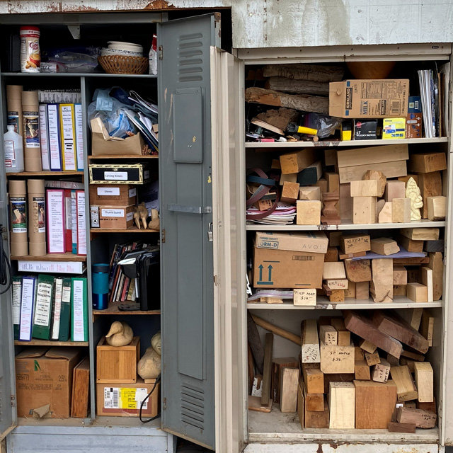 Two open cabinets with shelves full of wood and woodcarving supplies. The picture is taken for the Tri-Valley Carvers’ Newsletter.